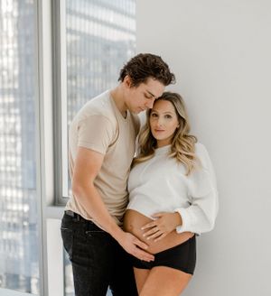 A couple embraces near a bright window in a modern apartment setting.