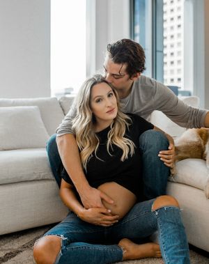 A tender moment captured between a couple on a white couch with city views in the background.