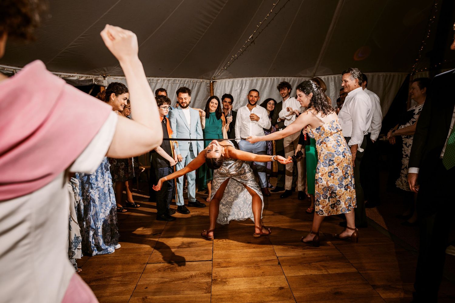 Wedding reception dance party with guests in motion on wooden dance floor.