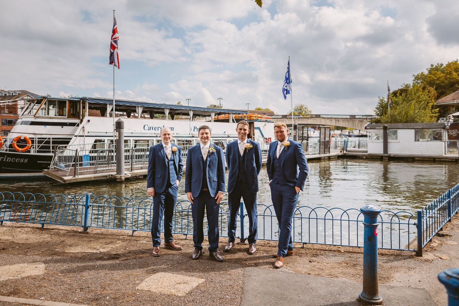 Wedding party posed at a marina with boats and flags in the background.