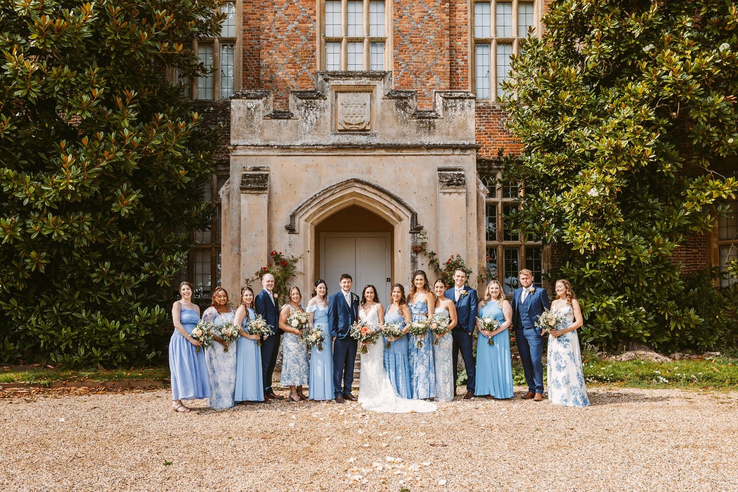 Wedding party poses in front of Gothic stone architecture wearing shades of blue and white.