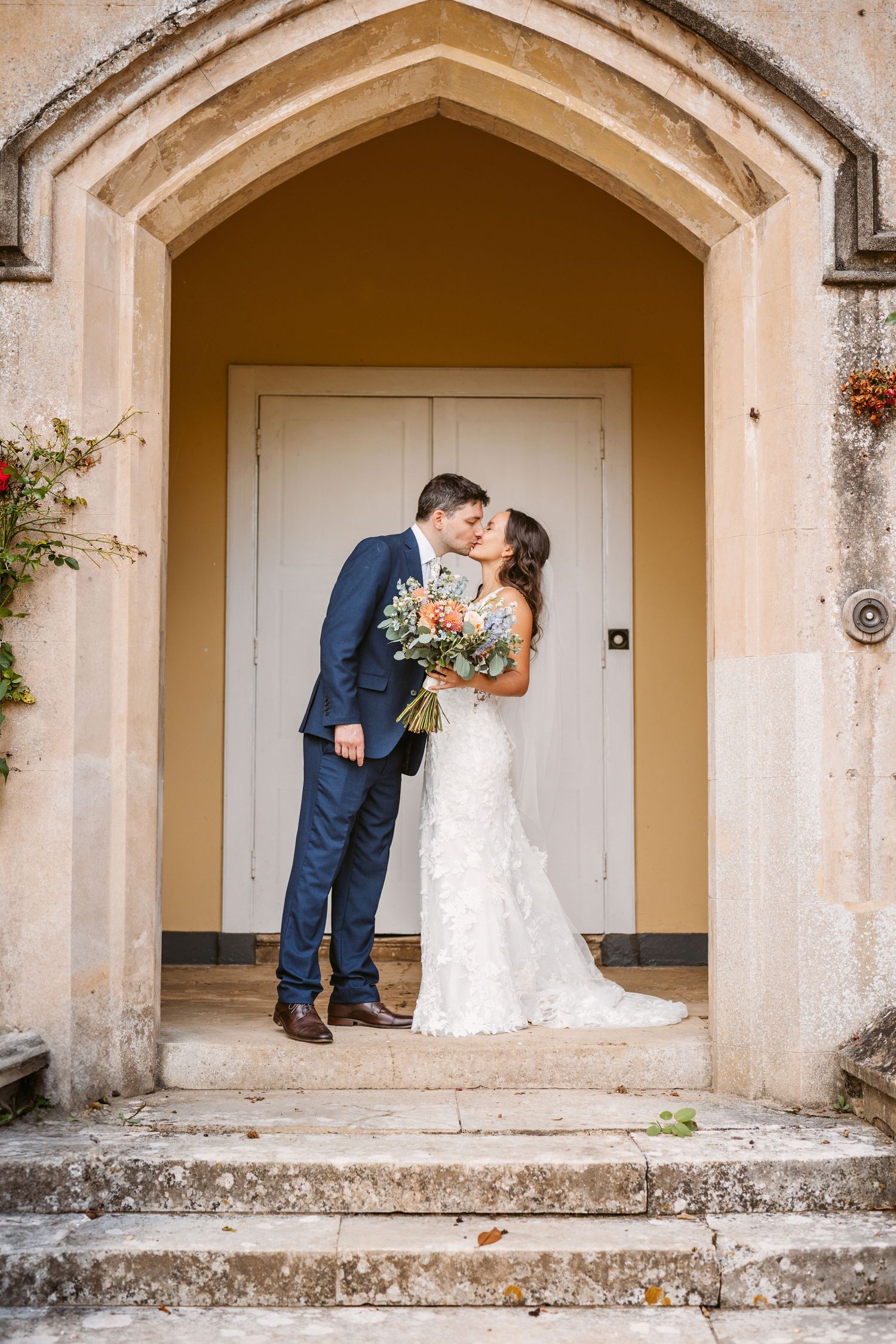 Young beautiful wedding couple kiss in the doorway of Mapledurham stately home