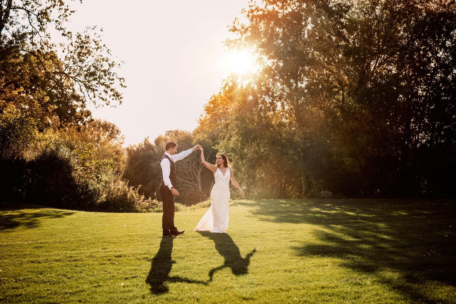 Dancing in golden sunset happy and in love newly wed bride and groom at Mapledurham