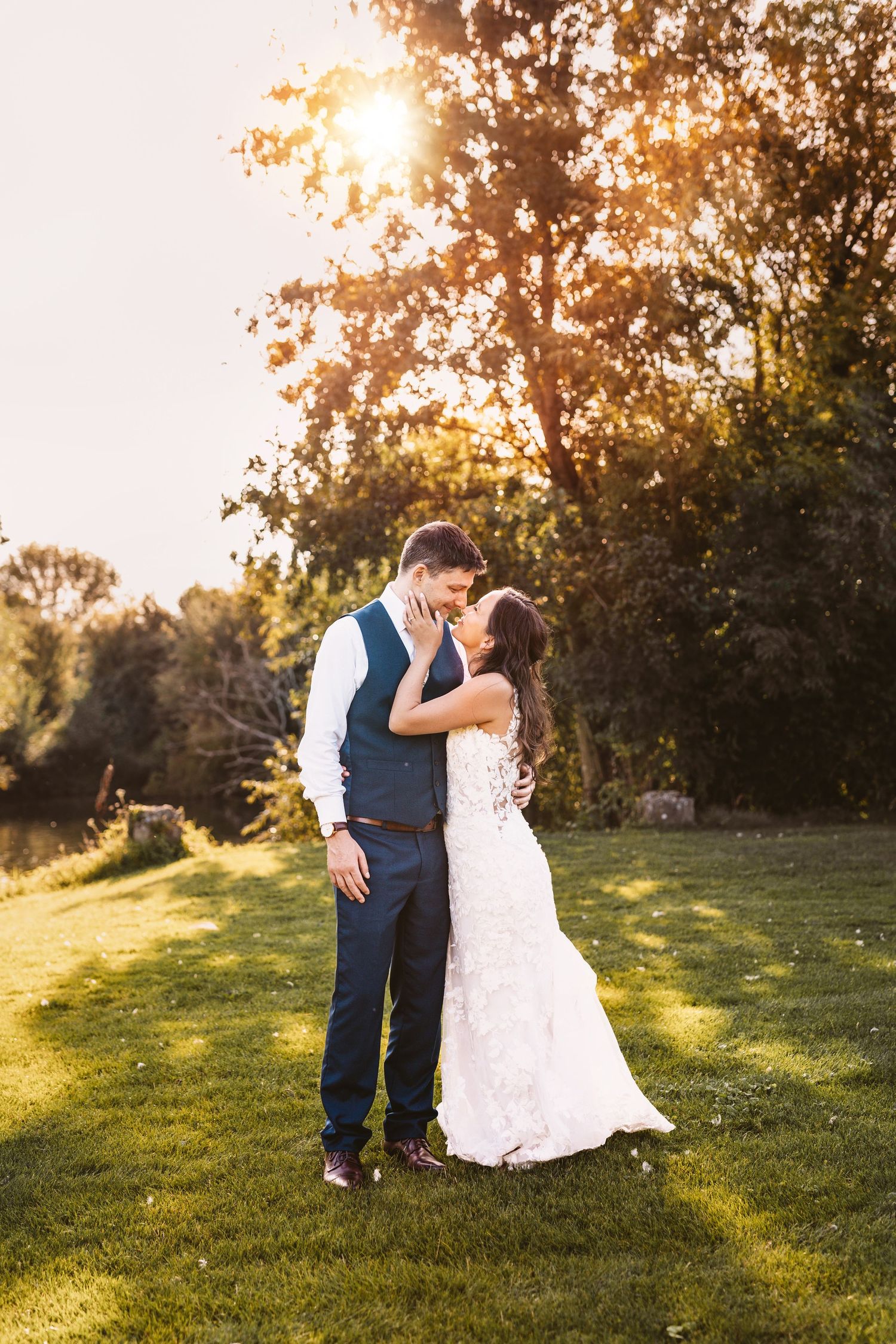 Kissing in golden sunset happy and in love newly wed bride and groom at Mapledurham