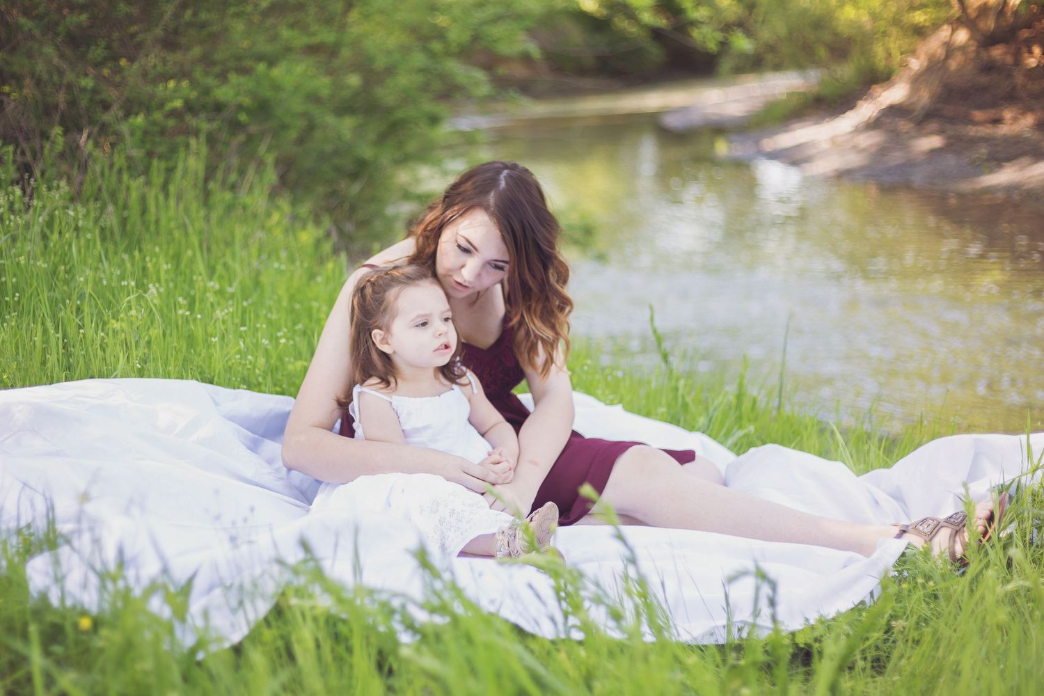 A tranquil reading moment on a blanket by the riverside in springtime.