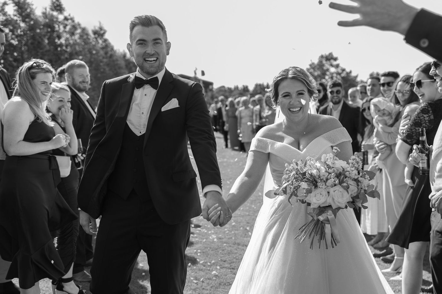 Bride and groom walking with guests throwing confetti