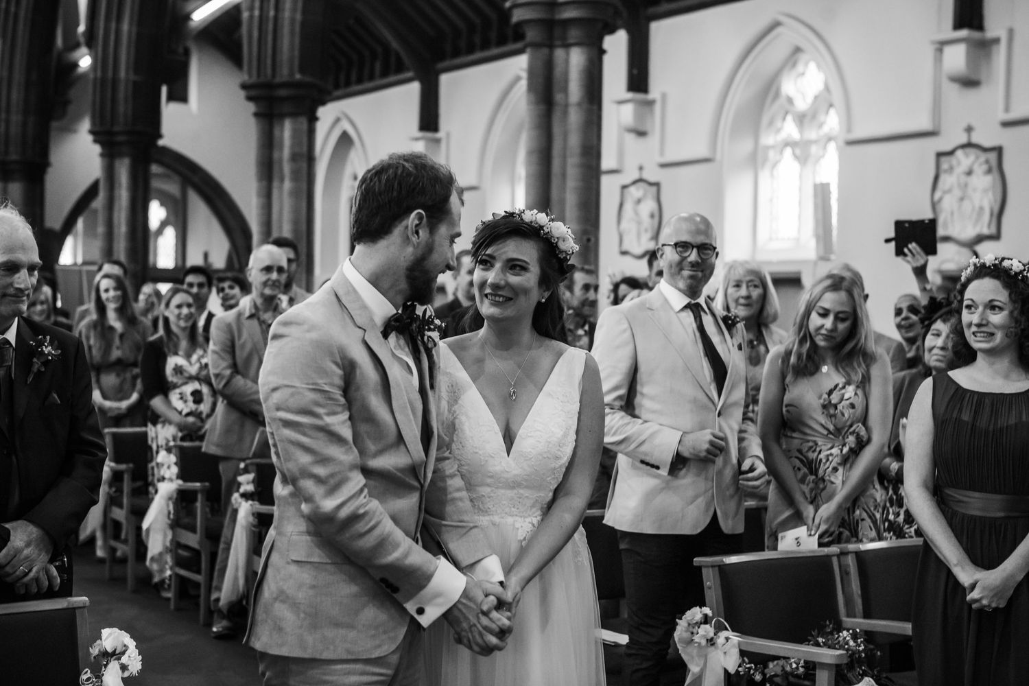 Black and white photo of a wedding ceremony in a traditional church with arched windows.