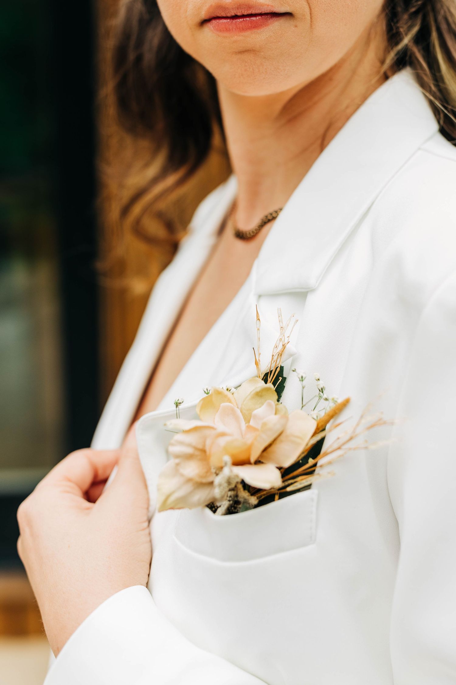 Delicate peach flower boutonniere pinned to a crisp white blazer lapel.