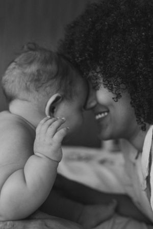 Intimate black and white moment between baby and caregiver with curly hair.