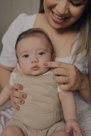 Sweet bonding moment with baby wearing beige romper during indoor photoshoot.