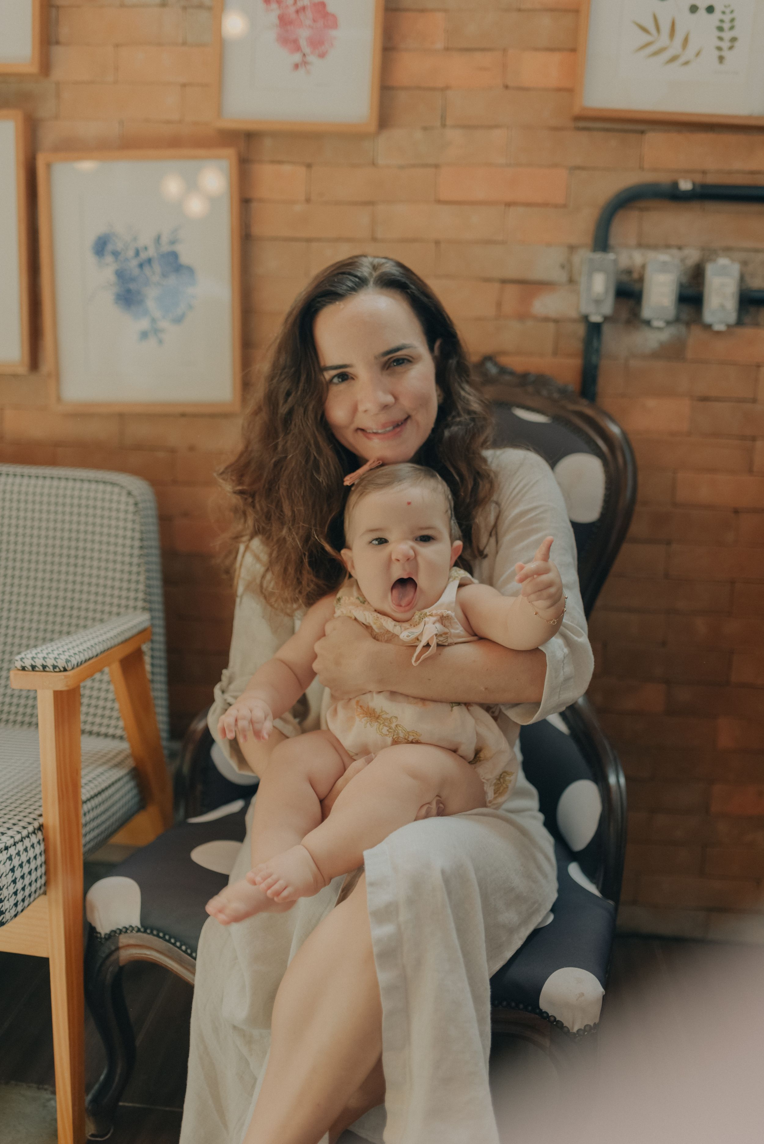 Heartwarming indoor portrait of parent and infant sitting in polka dot chair.