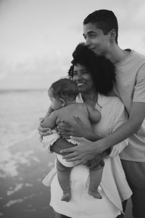 Family enjoying a tender moment together at the beach while holding their baby.