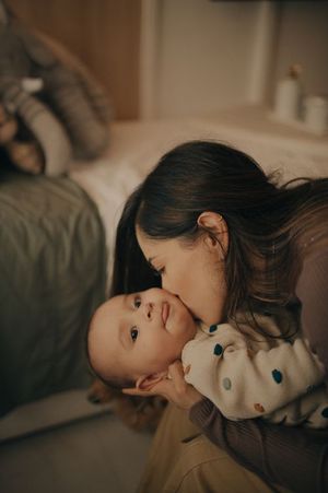 Intimate moment between parent and baby in polka dot outfit on couch.