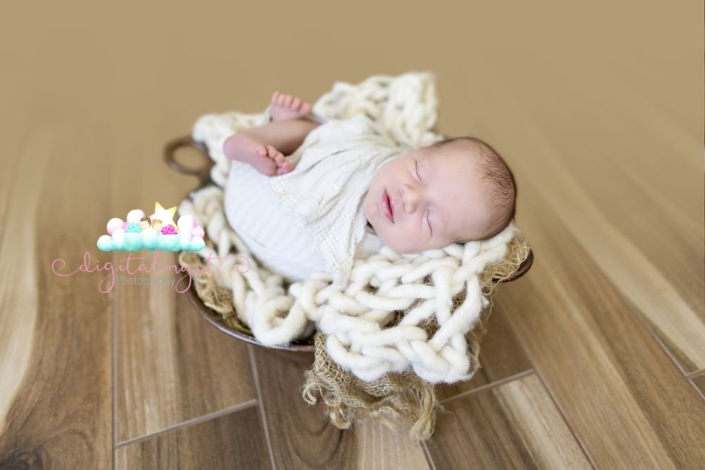 Professional newborn photography session featuring navy blue blanket and soft props.