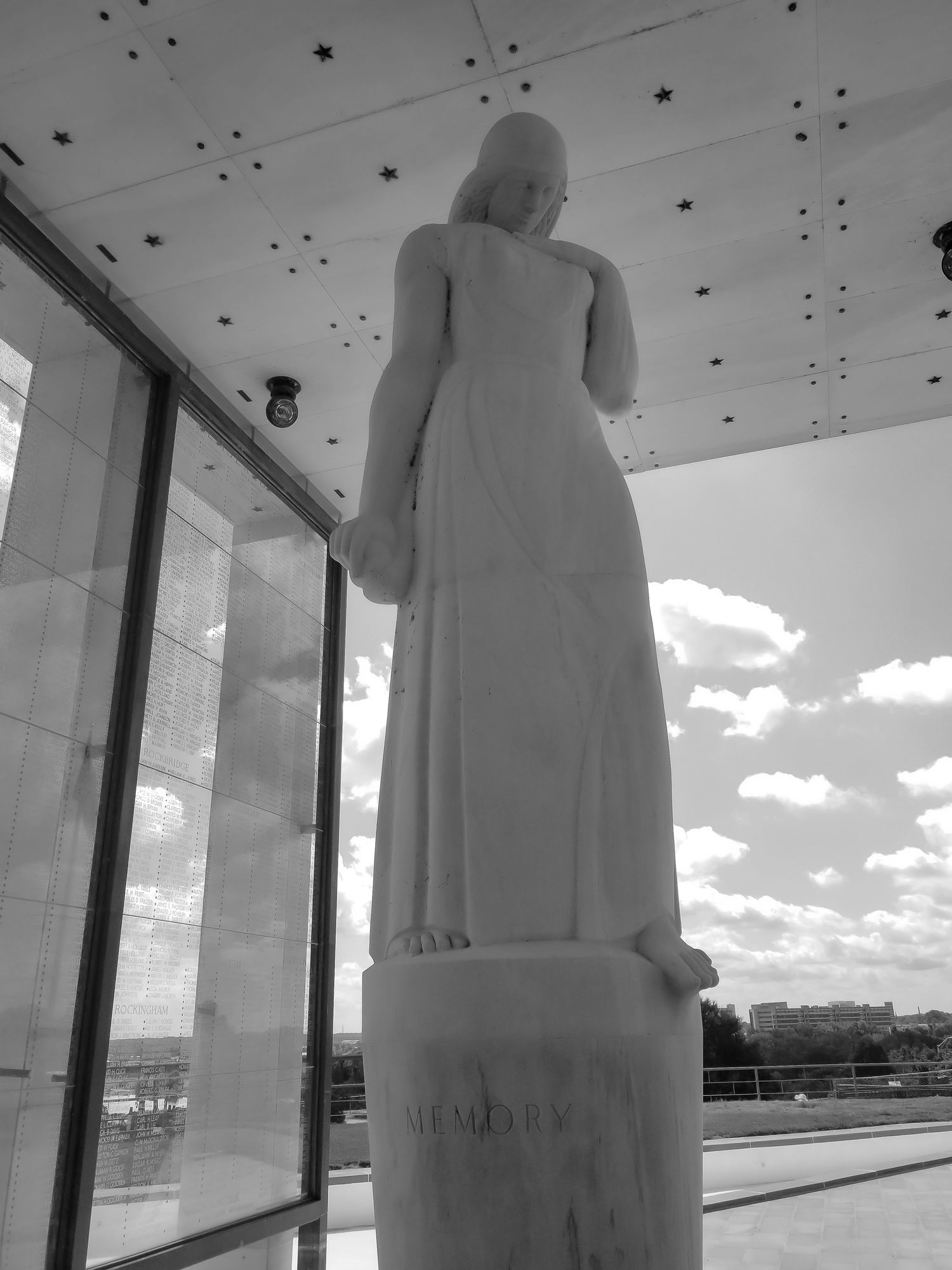 Black and white photo of a tall marble statue silhouetted against a cloudy sky.