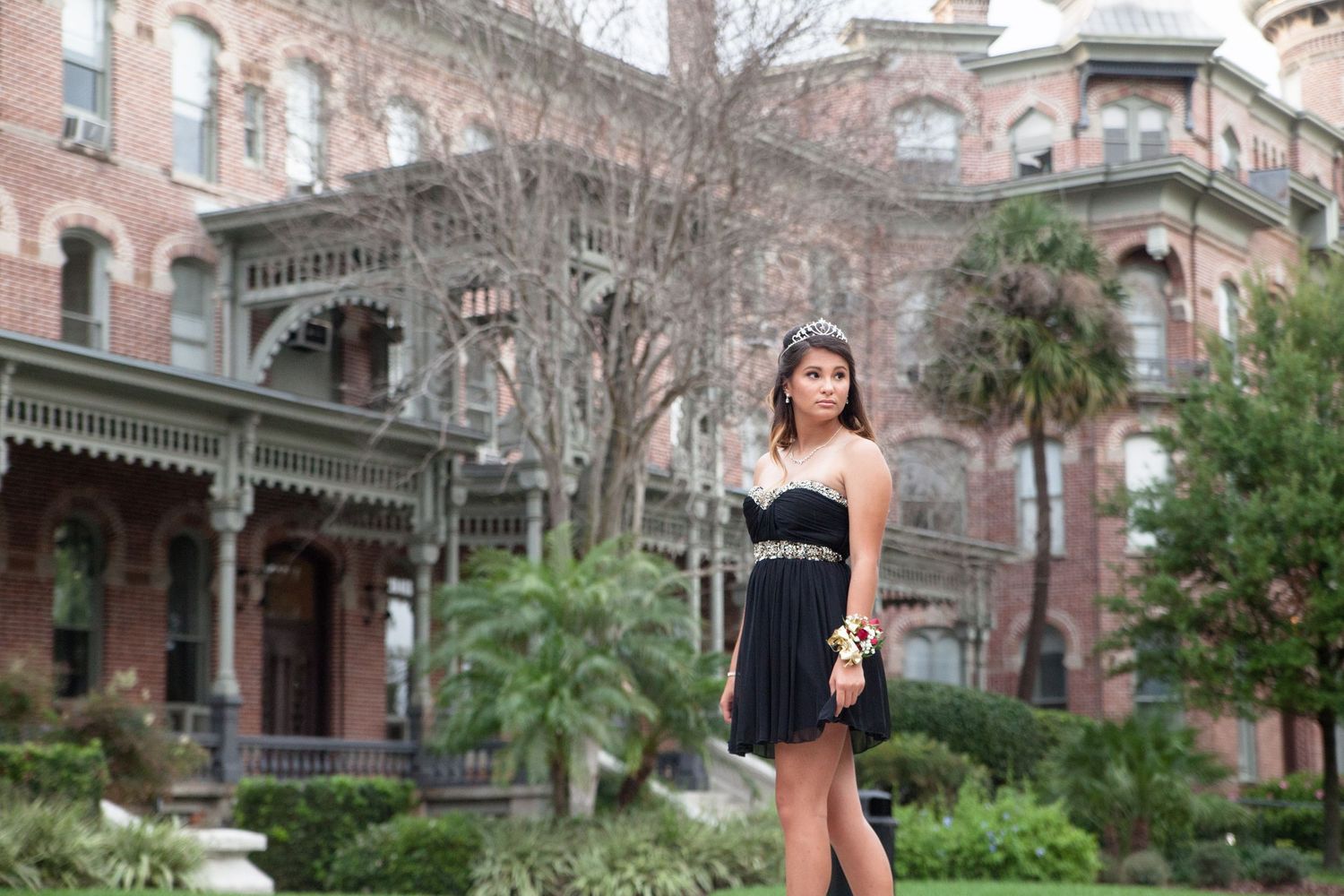 Teen girl in black dress with a flower corsage standing outside of the University of Tampa.