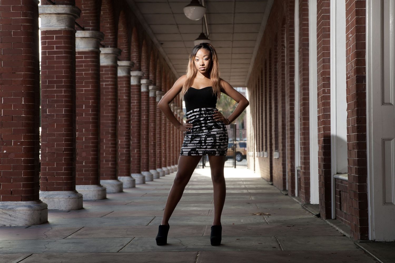 Girl wearing black and white dress posing in the corridor of Ybor City.