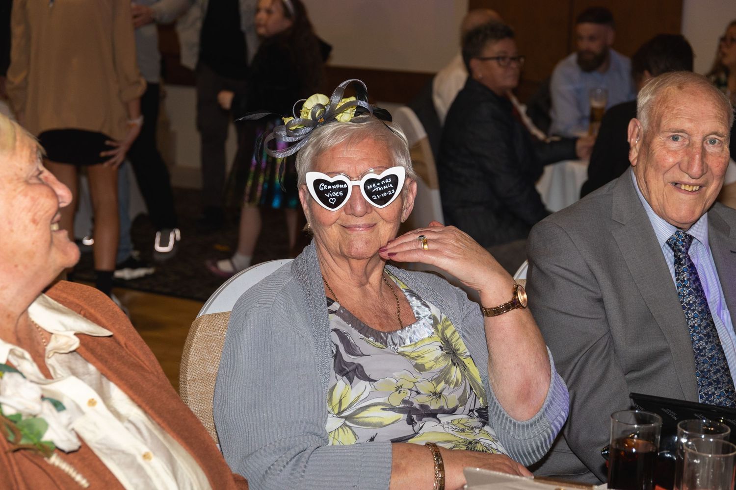Guest in floral print wearing heart-shaped sunglasses poses at formal dinner event.