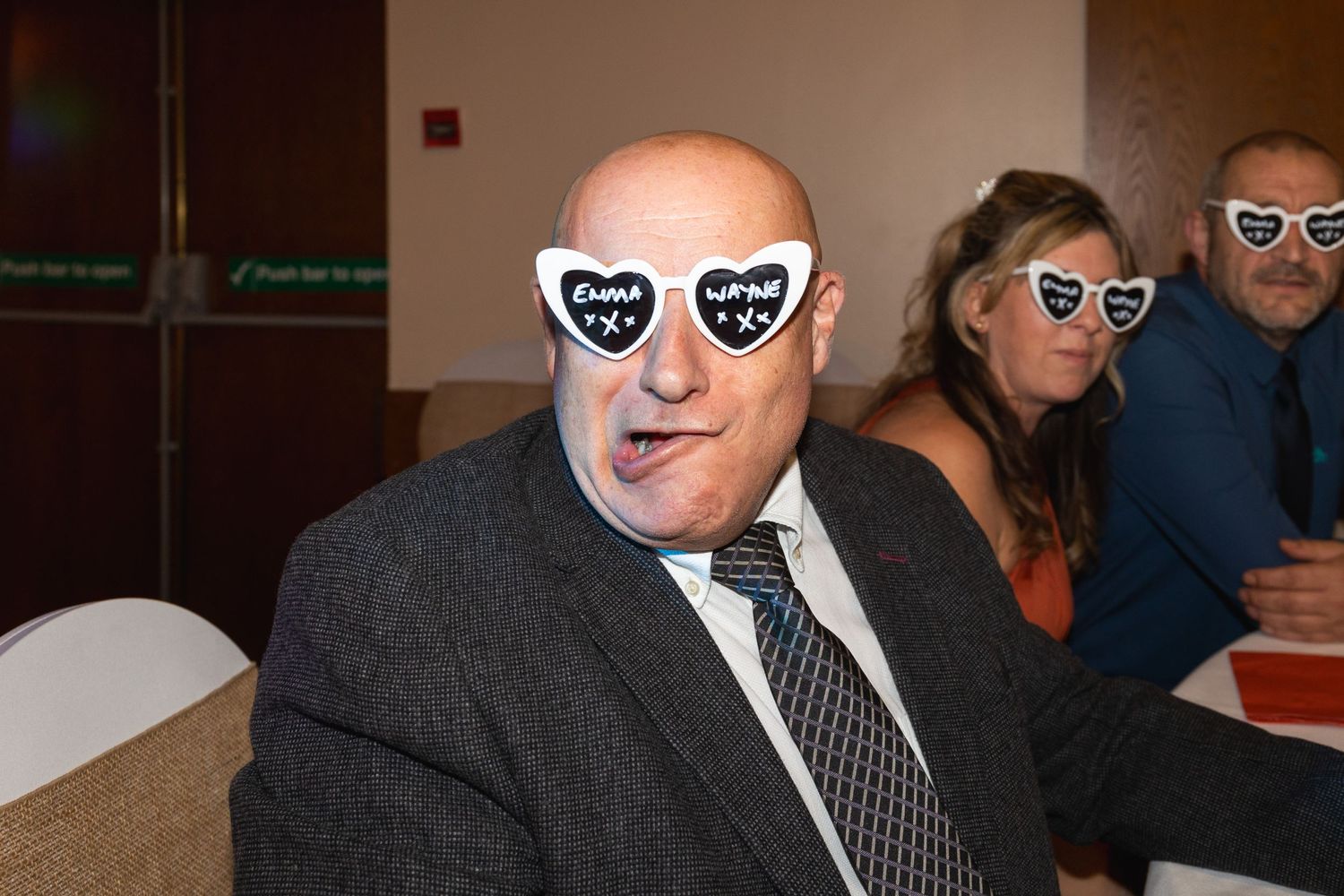 Group wearing matching heart-shaped sunglasses at an indoor gathering.