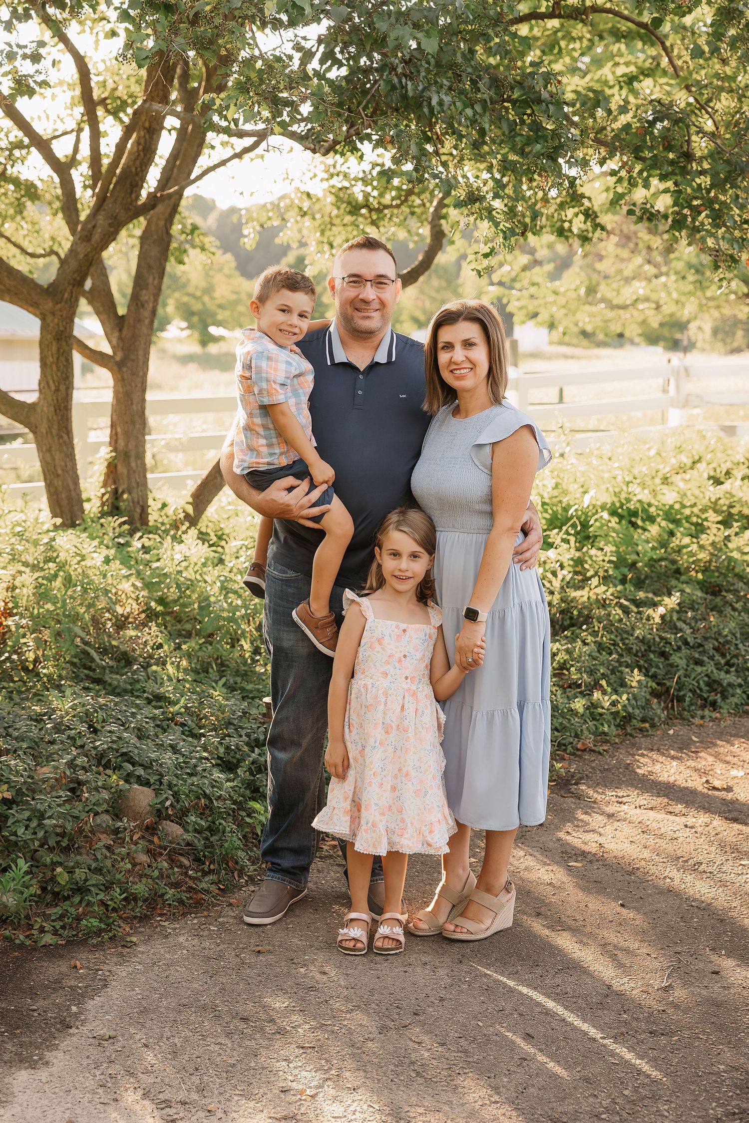 Family of four poses together on nature path during golden hour.