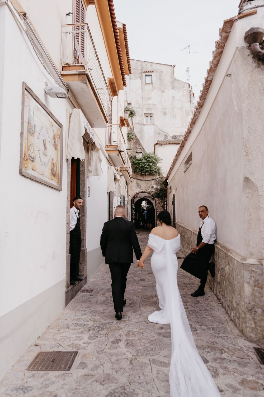 A charming narrow cobblestone alleyway between white buildings in an Italian village.