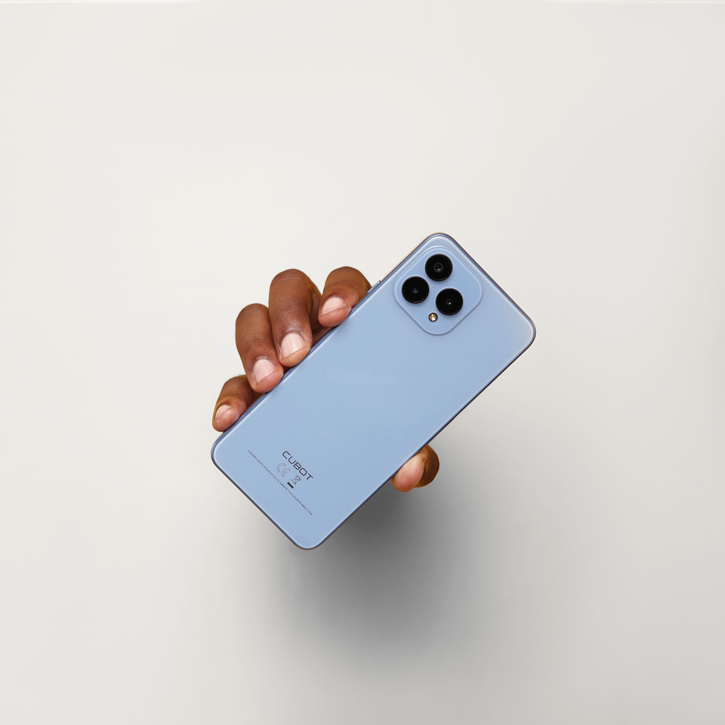 A light blue smartphone with triple camera lens being held against white background.