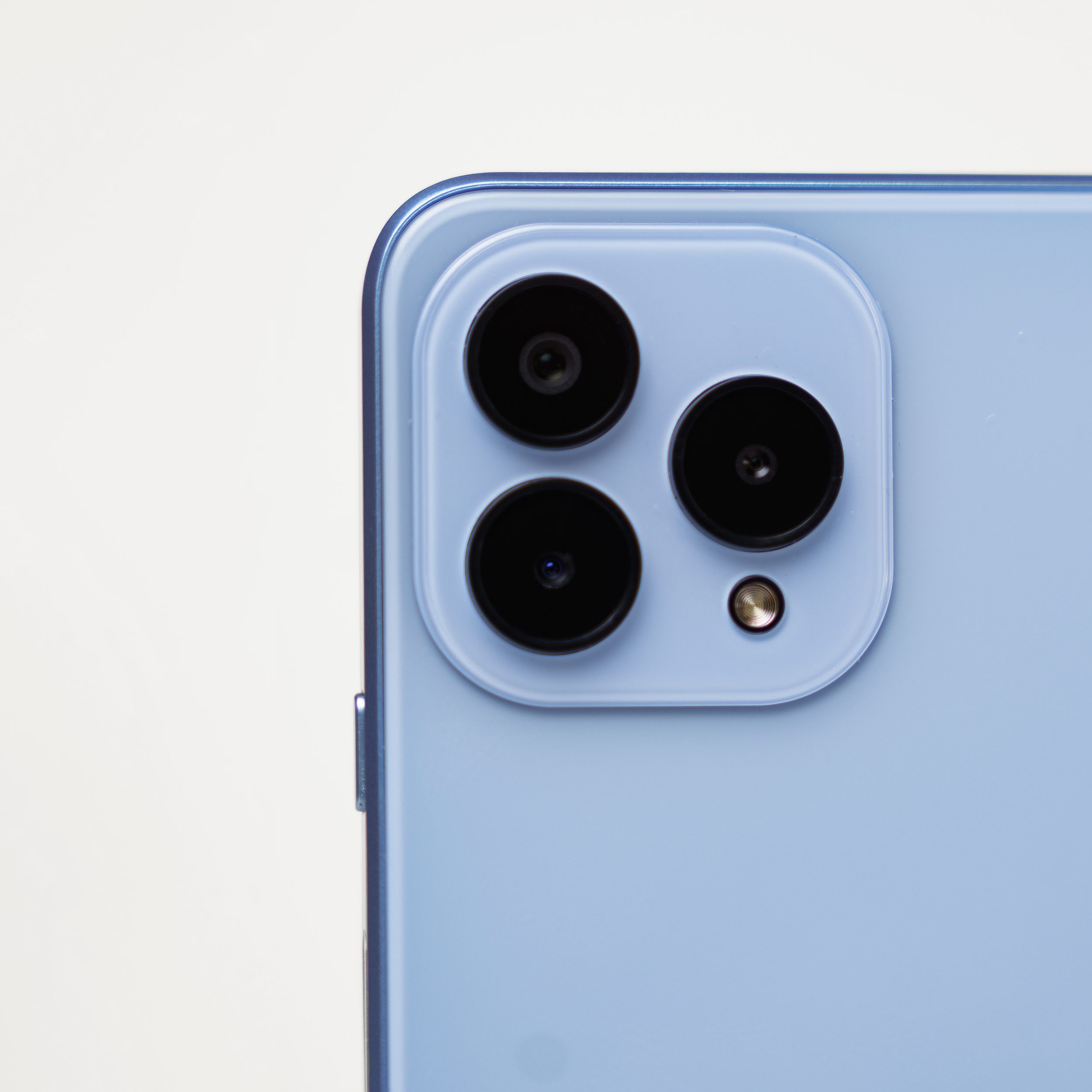 Close-up detail of triple camera system on light blue smartphone.