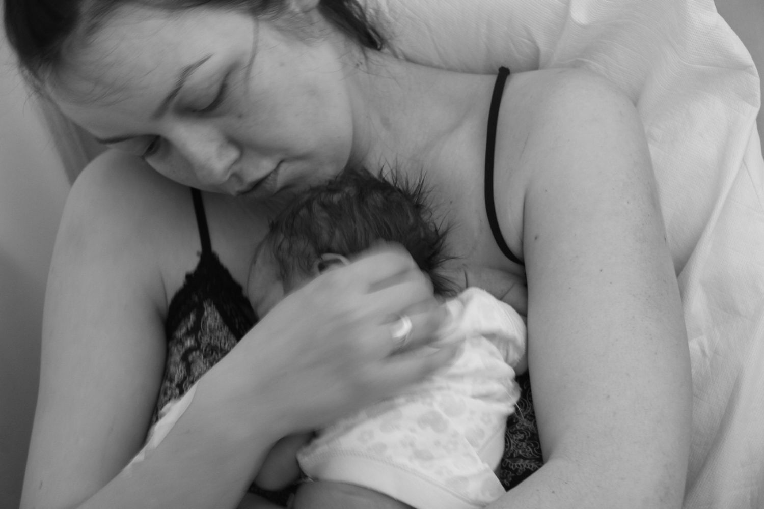 An intimate black and white photograph capturing a tender newborn moment.