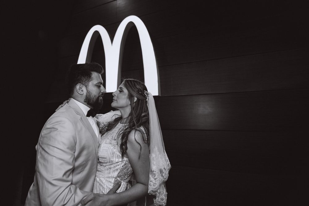 A couple sharing an intimate moment in front of illuminated McDonald's arches at night.