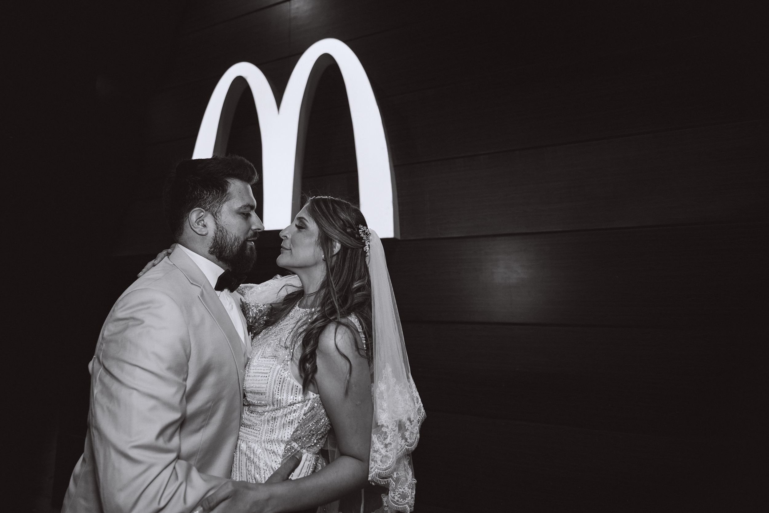 A couple sharing an intimate moment in front of illuminated McDonald's arches at night.