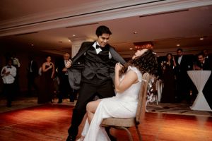 A playful wedding dance moment captured on a warm-lit wooden dance floor.