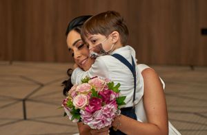 Tender embrace with pink and red floral bouquet at formal event.