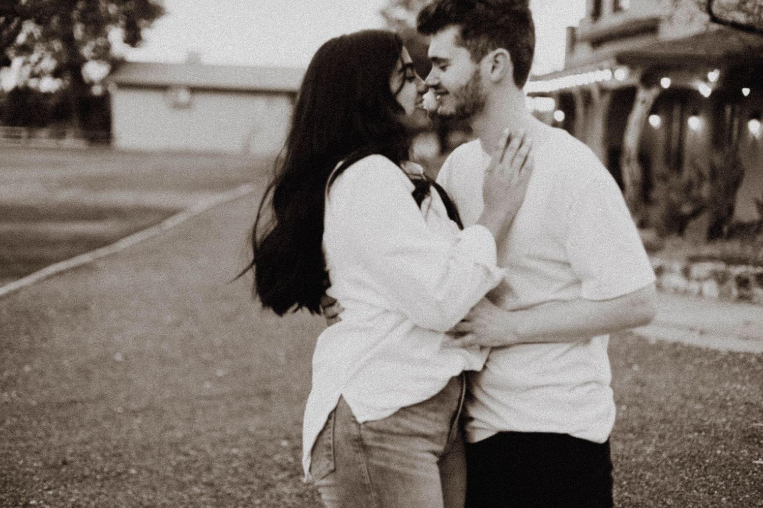 A romantic black and white portrait of a couple embracing outdoors.