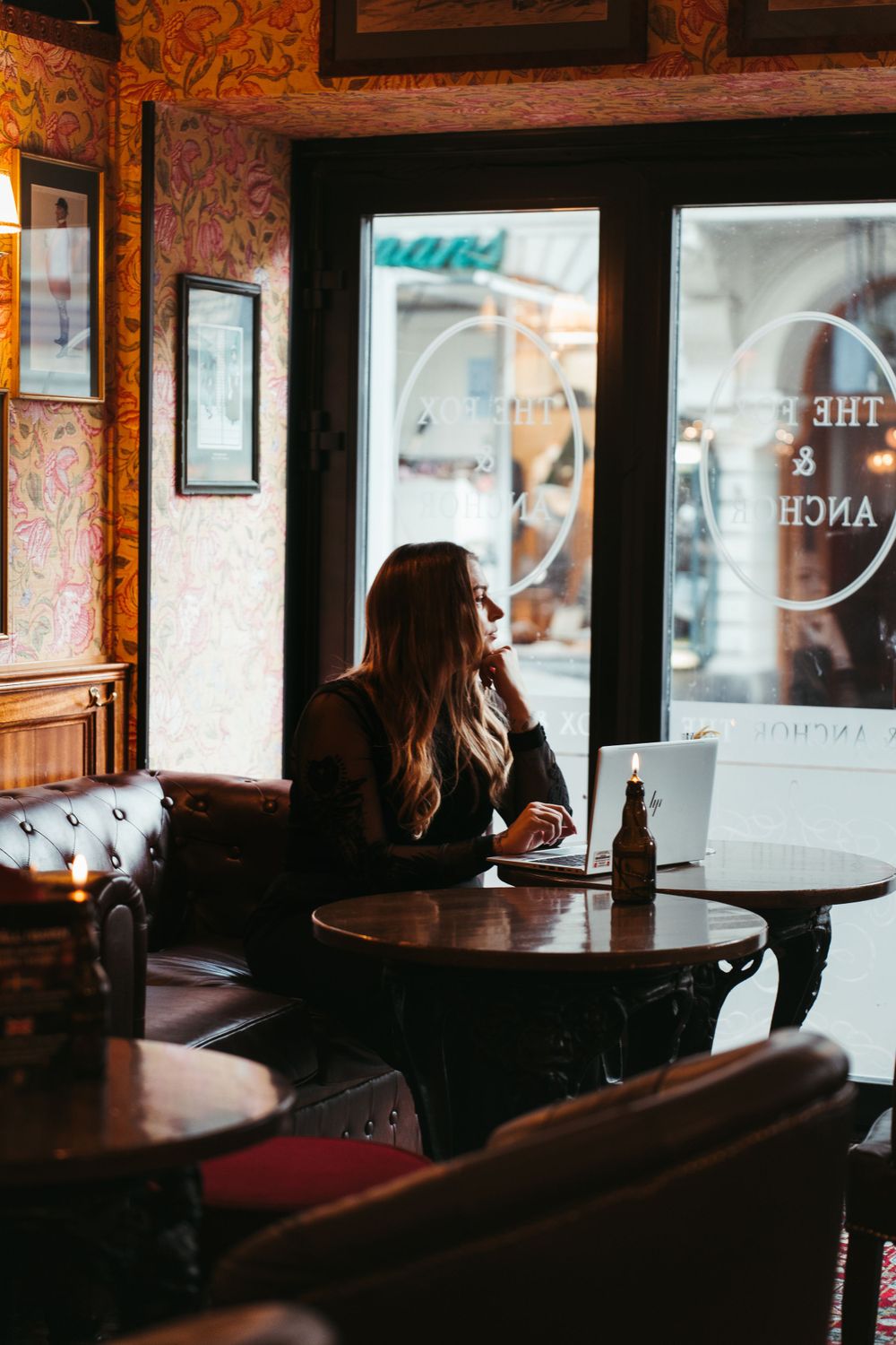 Cozy interior of a vintage pub with decorative wallpaper and window lighting.
