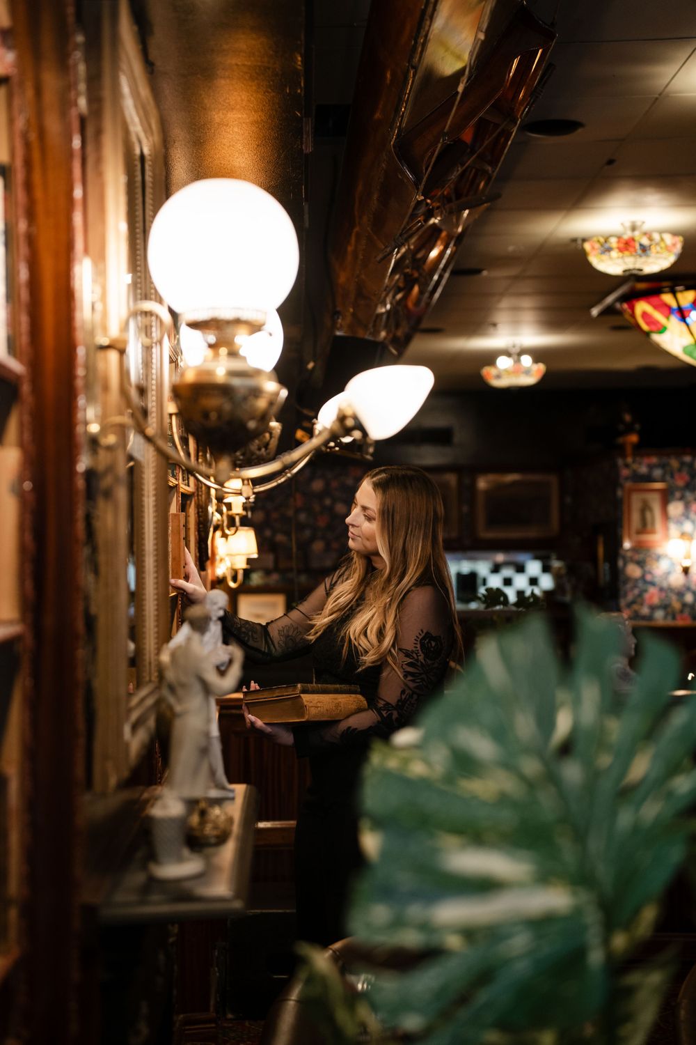 Atmospheric shot of a library bar interior with globe lights and tropical plants.