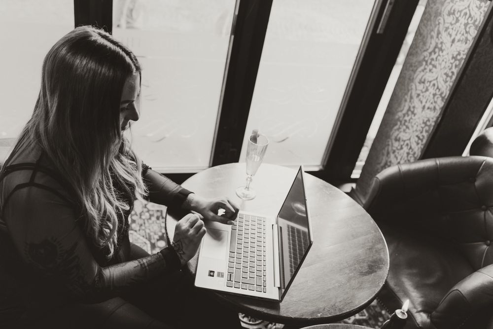 Black and white shot of someone working on a laptop in a vintage setting.