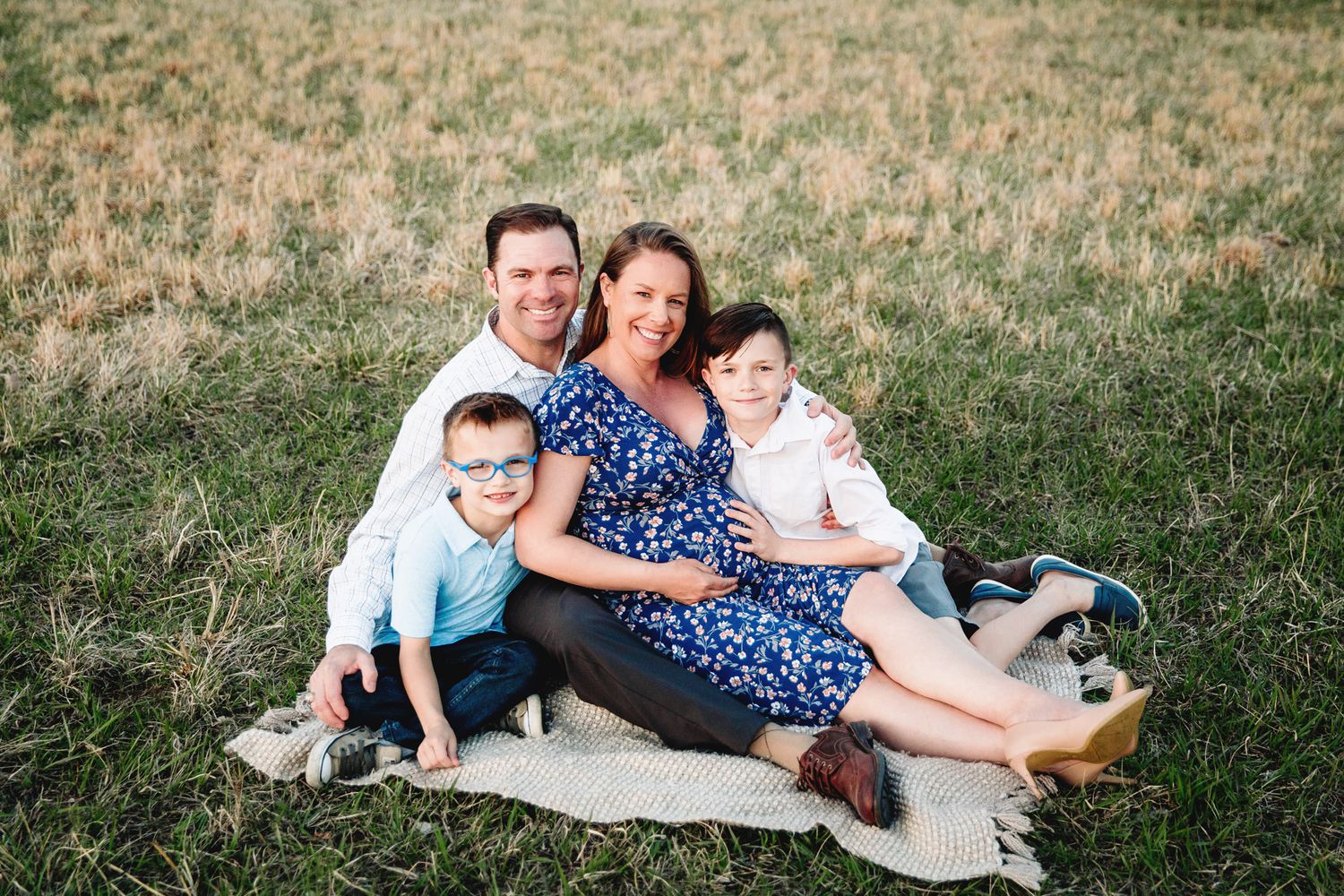 family sitting on blanket in grass