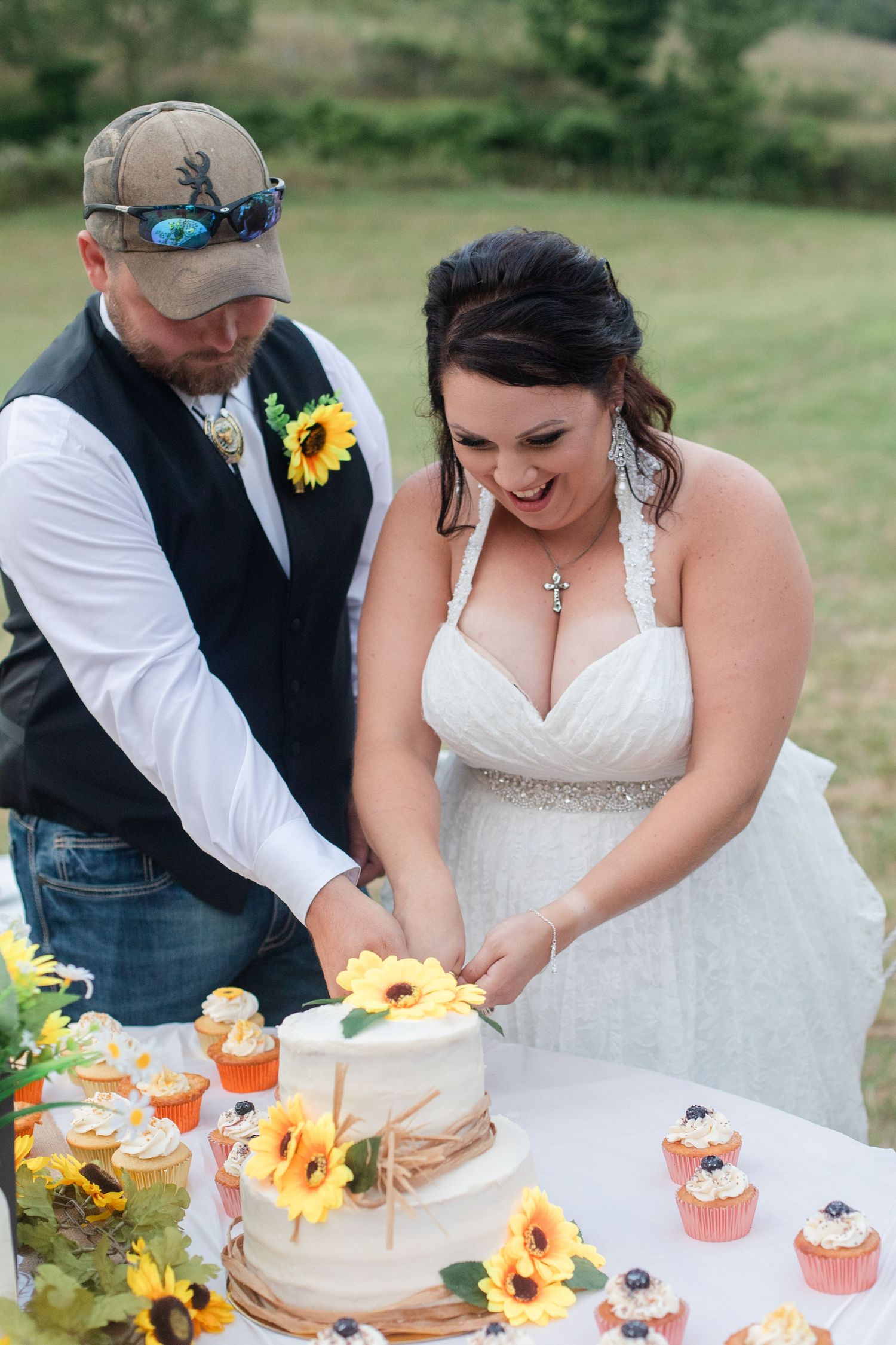 Bride and groom cutting their wedding cake decorated with sunflowers.