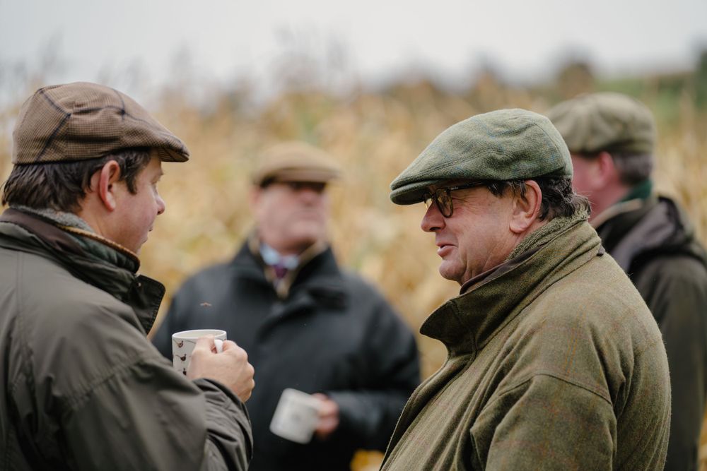 Hunters in traditional countryside attire having a conversation during a shoot.