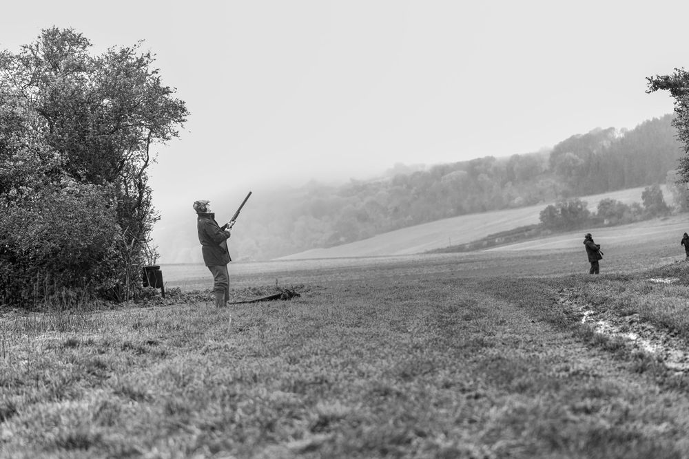 Hunters spread out across a misty field during an autumn hunting expedition.