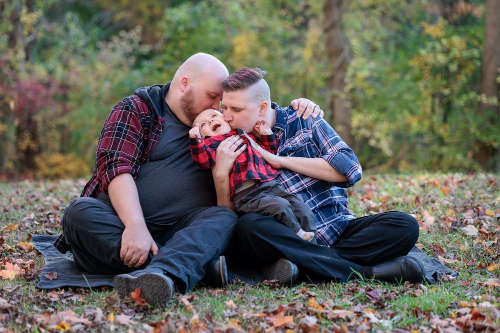 Family lying on autumn leaves in a park during a photo session.