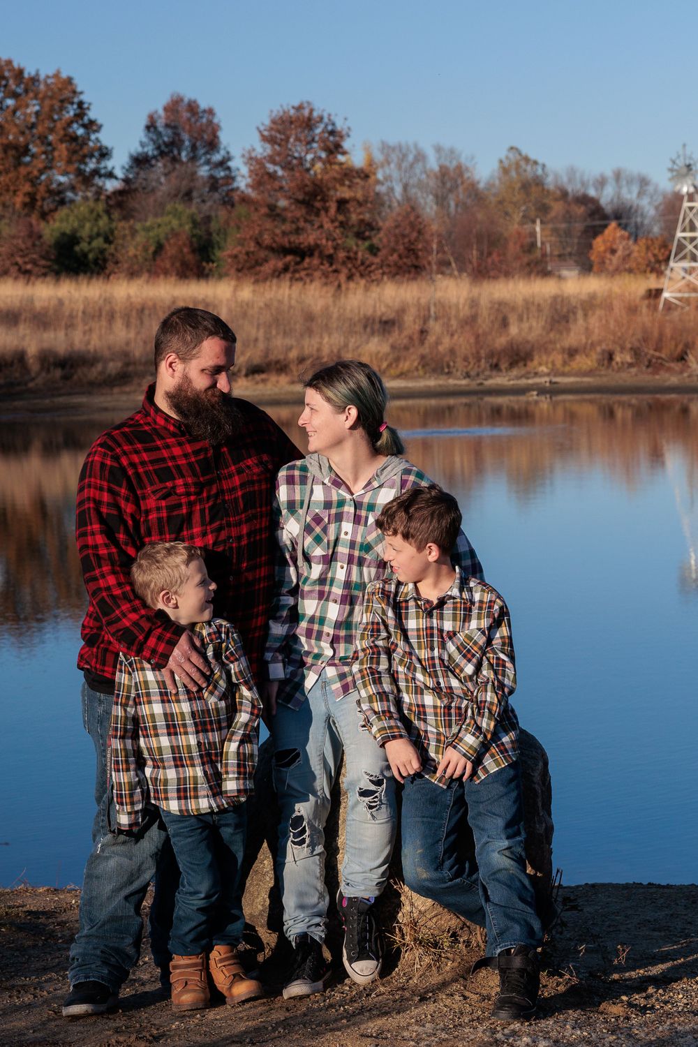 Group sitting by tranquil lake with autumn trees reflecting in calm blue water.