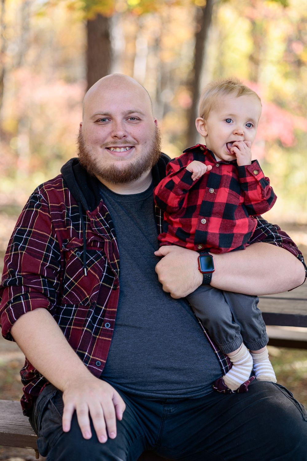 Family members in plaid and dark clothing sitting together outdoors.