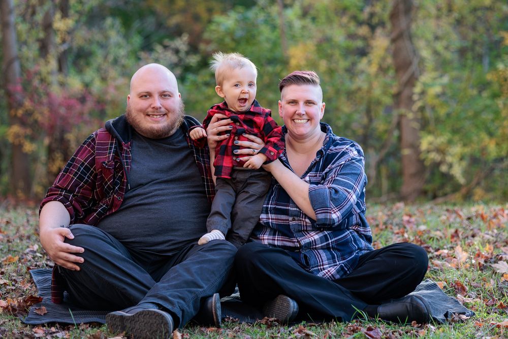 Family group relaxing outdoors on fallen leaves during autumn.
