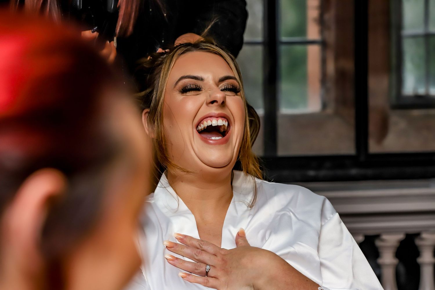 A candid moment of joyful laughter during wedding preparations.