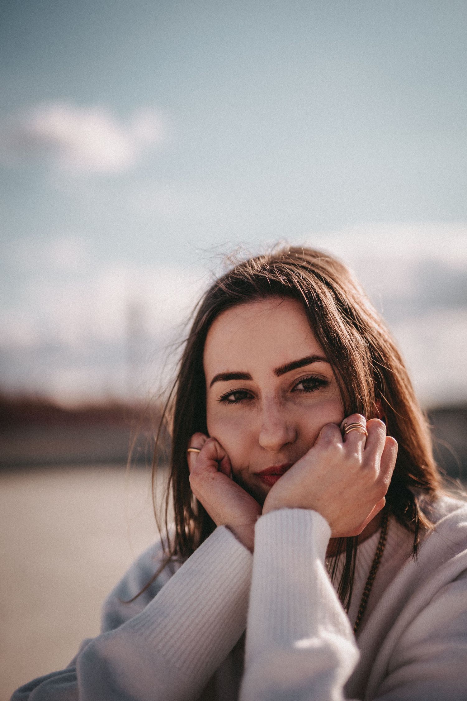 Portrait in a cozy white sweater against a soft sunset background.