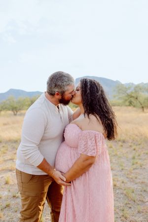 A loving embrace captured against a scenic desert backdrop with mountains and brush.