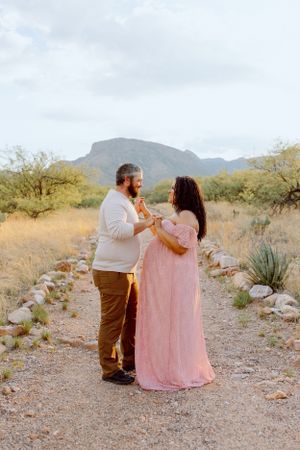 A couple shares a dance moment on a desert trail surrounded by natural desert landscape.