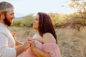 A joyful couple dances together in a desert setting with mountains visible behind them.