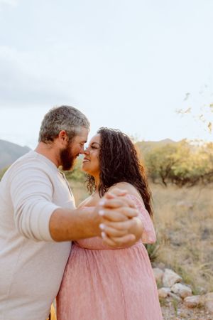 A romantic dance pose captured in a desert setting with mountains and cacti.